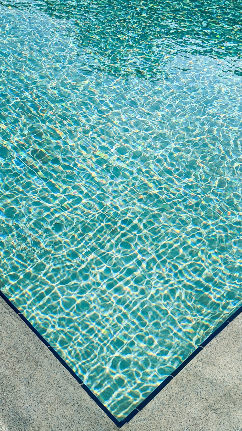 Angle de bassin, eau turquoise et margelle pierre